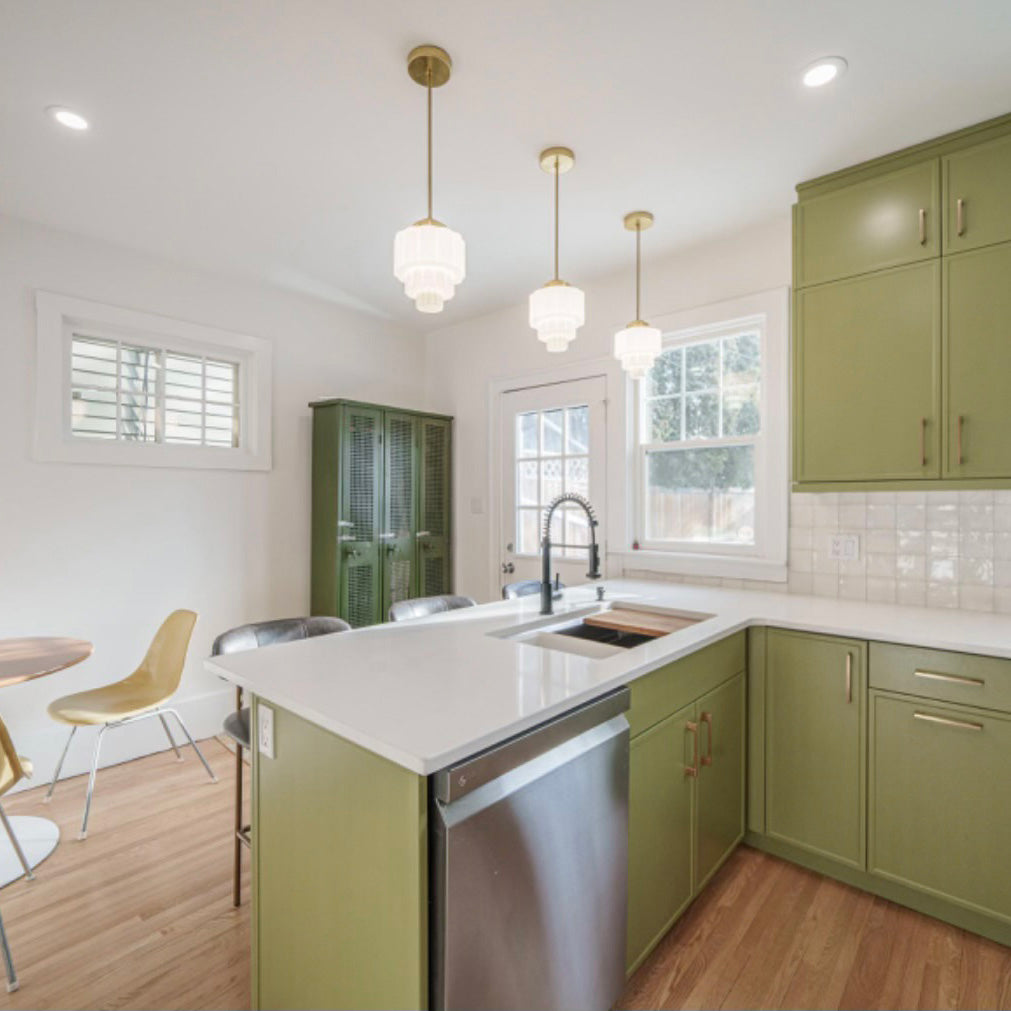 Well lit and clean green, white, and gold kitchen.