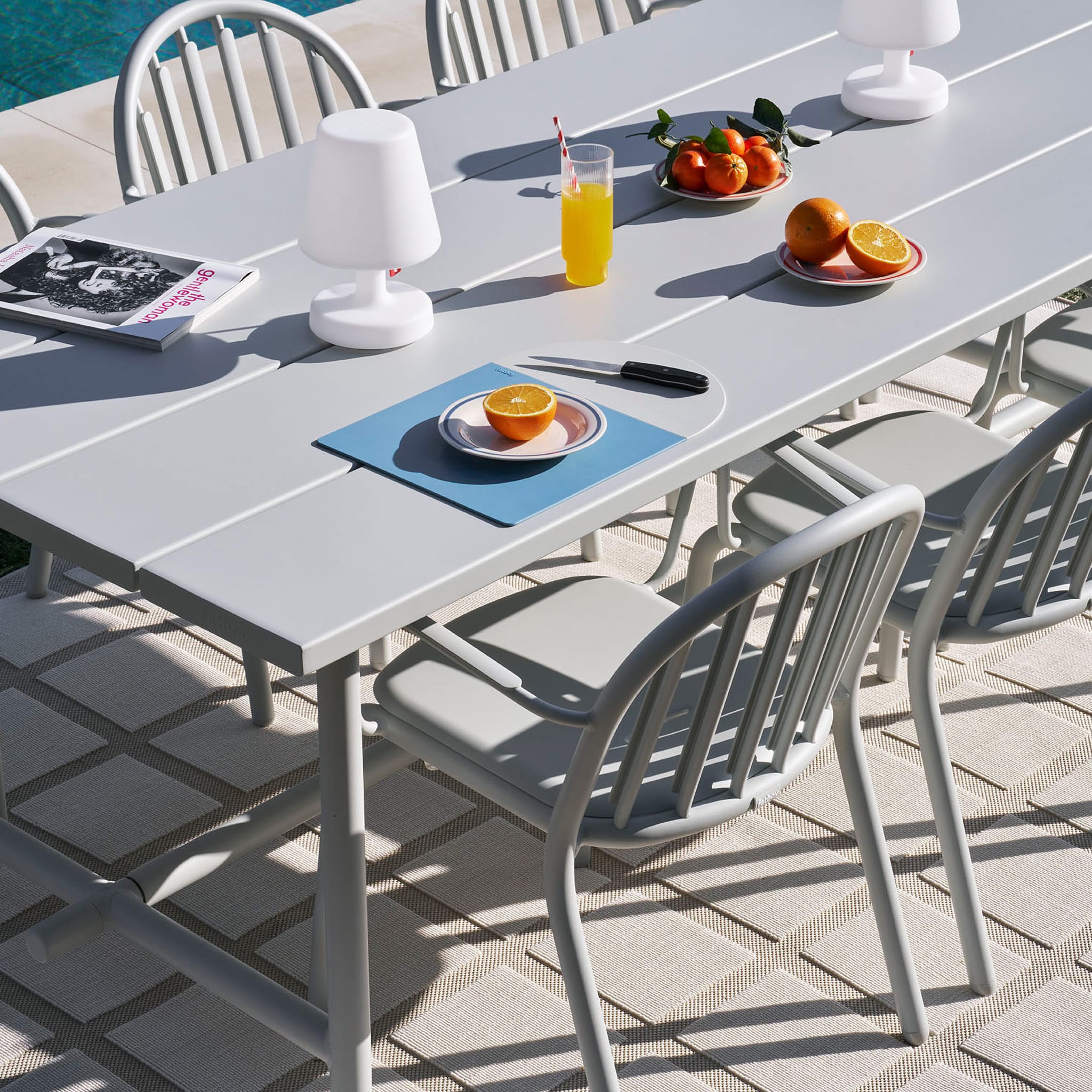 Fred’s Armchair in a modern patio setting, showcasing its sleek aluminum design and weather-resistant features.
