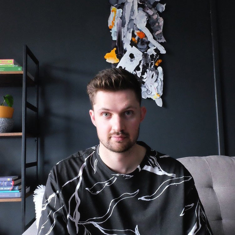 Jordan Baraniecki sitting in front of one of his abstract paintings.