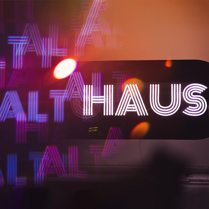 Abstract photograph of a neon sign that reads 'Alt Haus'