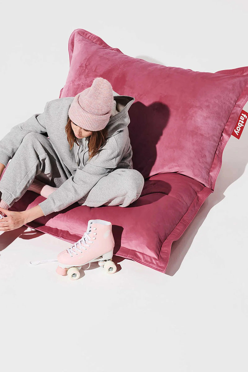 Woman putting on roller skates while sitting on a pink Fatboy bean bag.